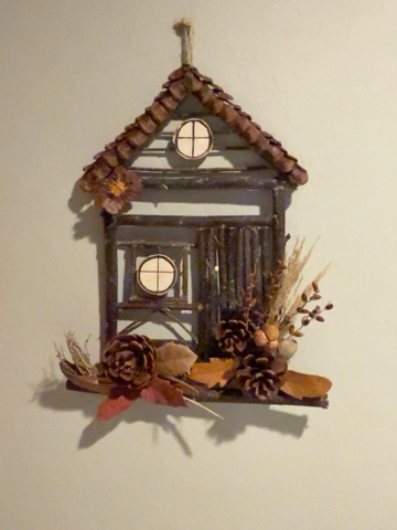 A little cottage built from twigs, with pinecones and natural details.